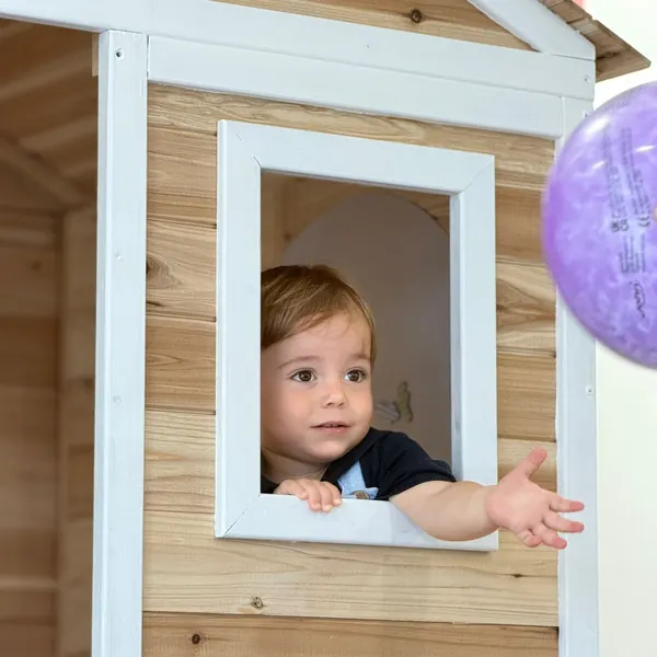 Criança à janela da casinha de madeira com um balão
