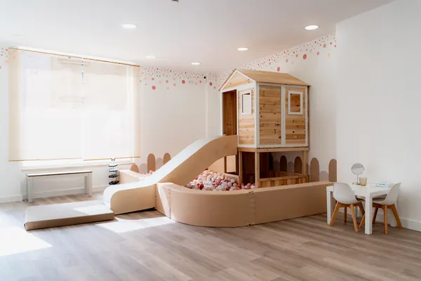 Sala principal com casinha de madeira, escorrega e piscina de bolas