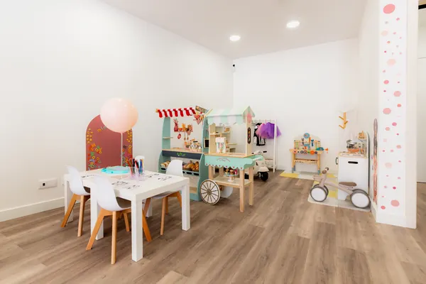Zona de brincadeira com mercearia de madeira, mesa de actividades e triciclo